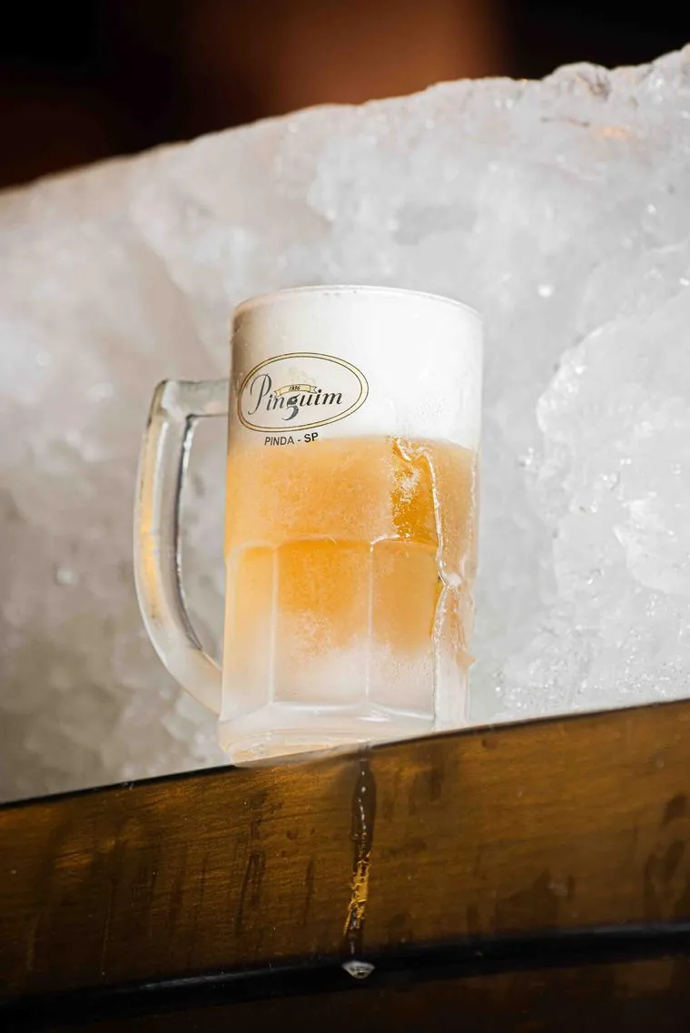 Caneca gelada de chopp Pinguim com colarinho cremoso, servida sobre o gelo